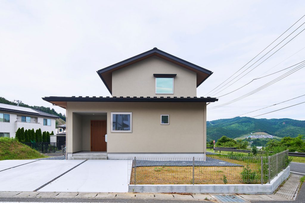 南側からの外観。シンプルなベージュ色の塗り壁が温かな風合いを醸し出す