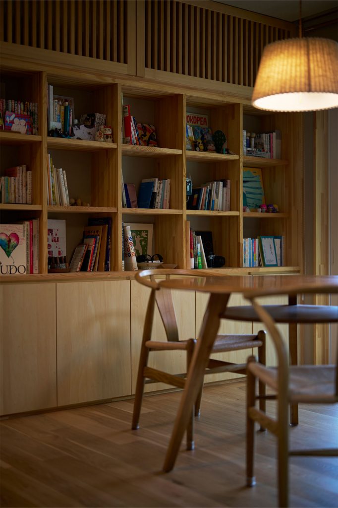 リビングには壁付けの本棚を造作。木の格子で目隠しされた上部にはエアコンが格納されている