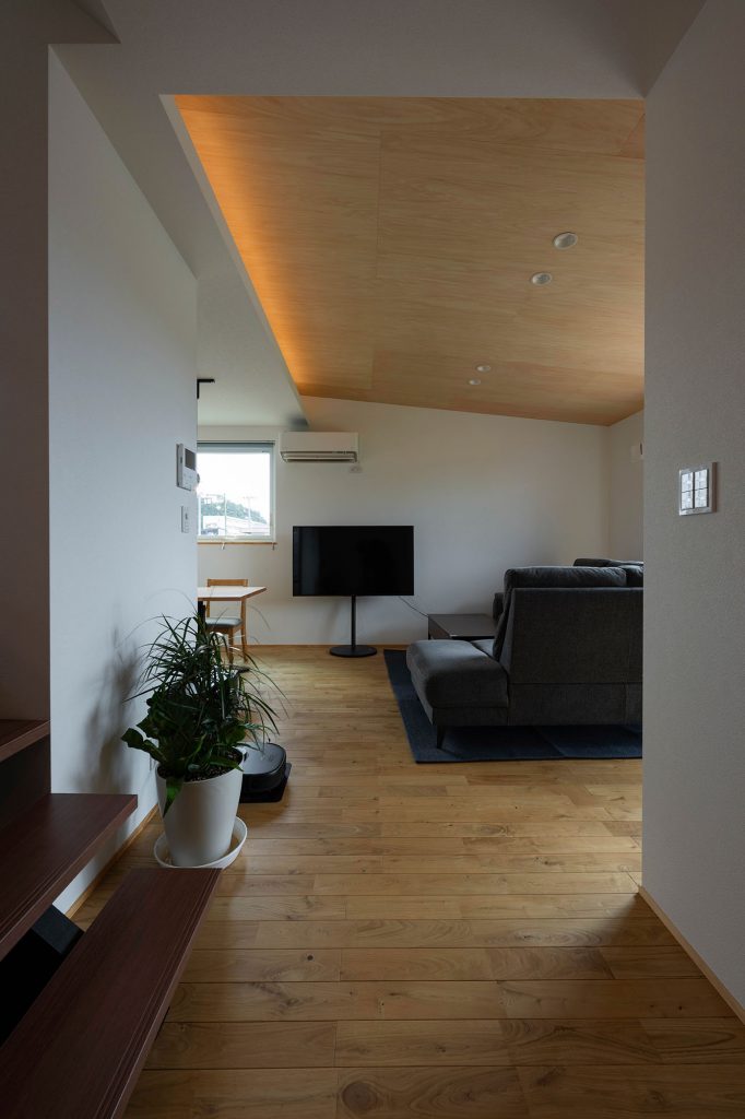 階段前からリビング方向を望む。シナベニヤを張った勾配天井が面積以上の広がりをもたらしてくれる