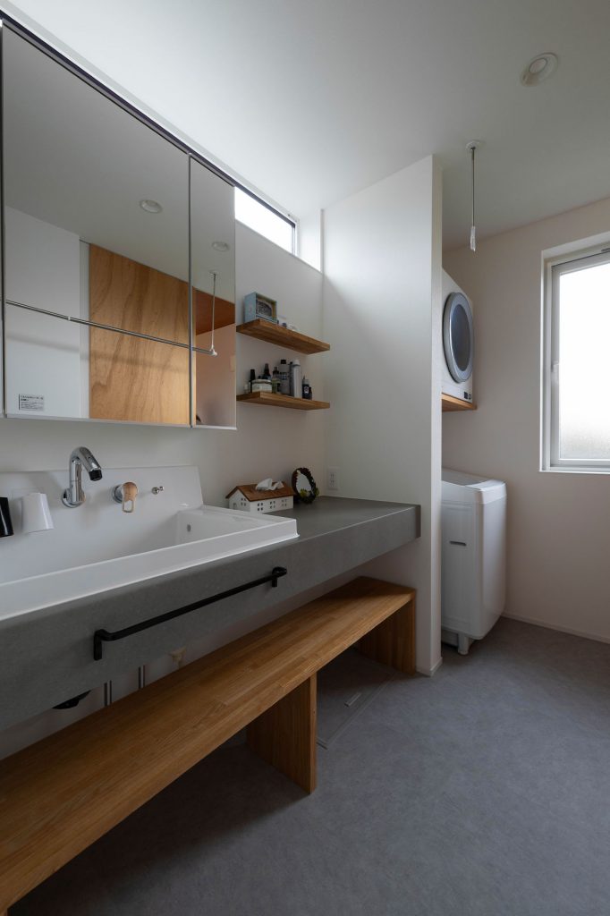 造作の洗面カウンターは、複数人が立っても使いやすい広々とした設計。洗面エリアは物干しスペースを兼ねていて、洗濯機の上部には衣類乾燥機を置く棚も設けた